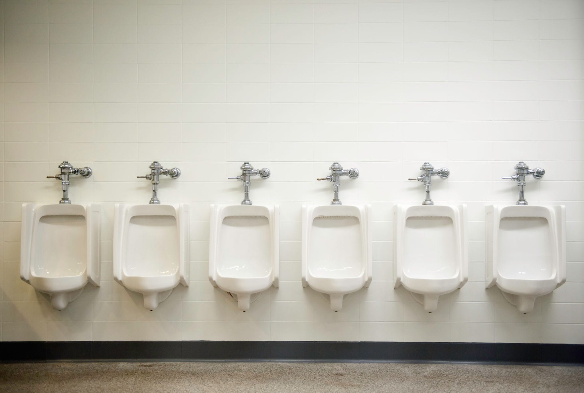 A row of six urinals await customers.